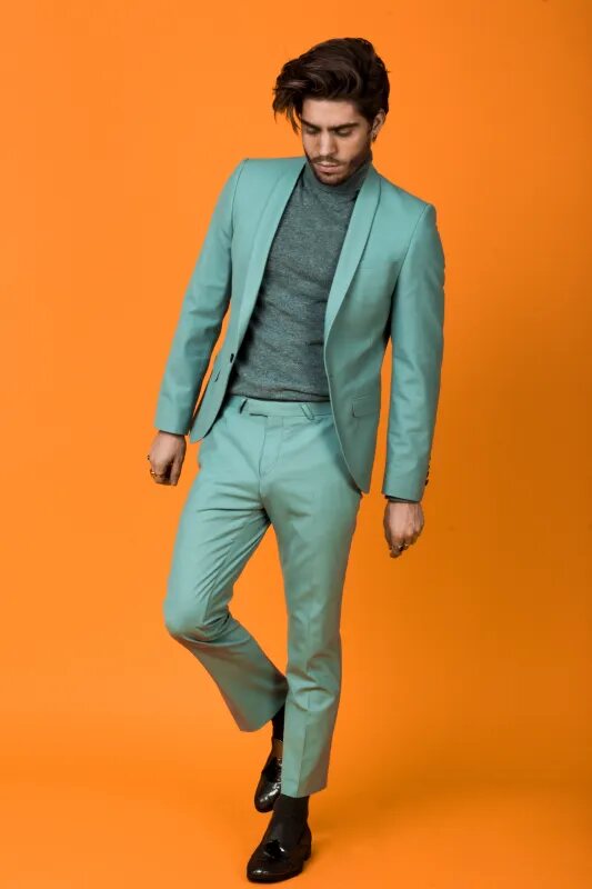 Model in a mint-green suit against a bold orange backdrop