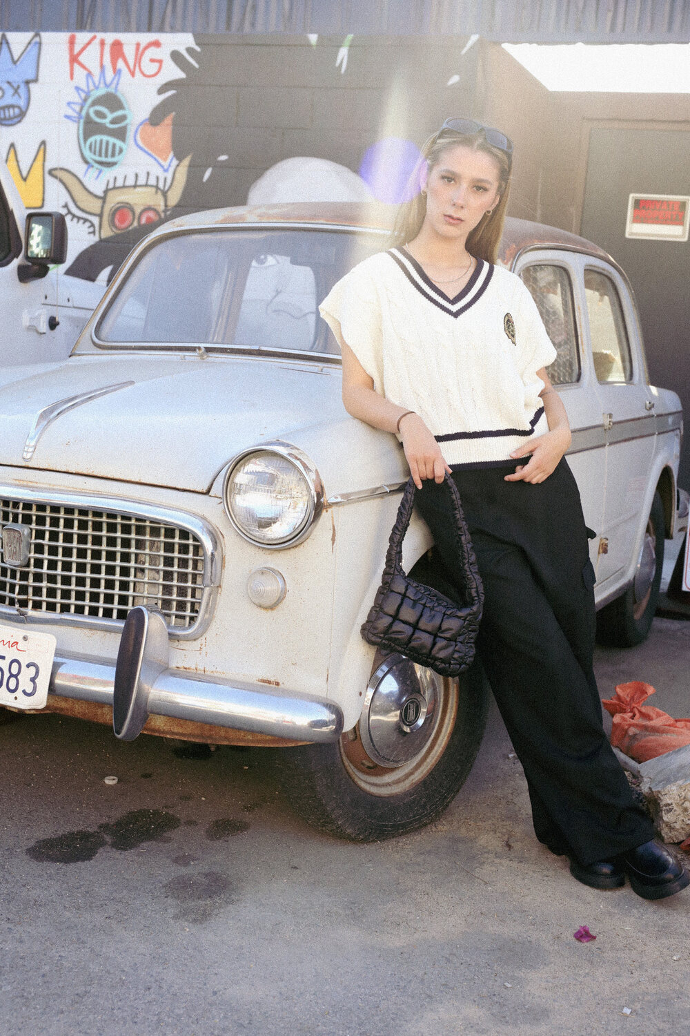 Model in relaxed streetwear beside a vintage cream car
